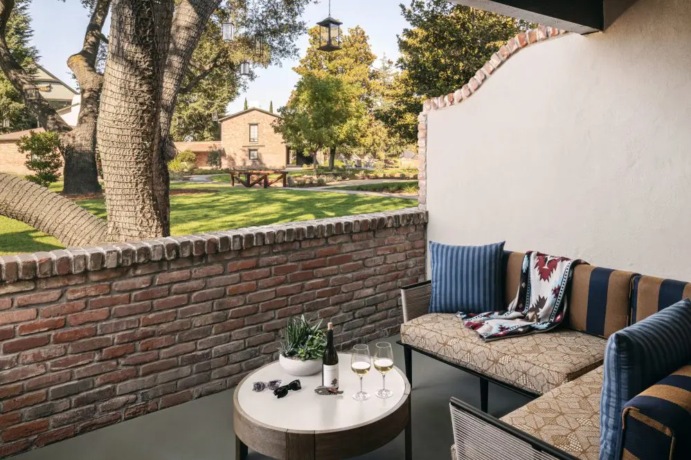 Garden Studio patio with round table with wine glasses and a couch looking out into the gardens at Paso Robles Inn.