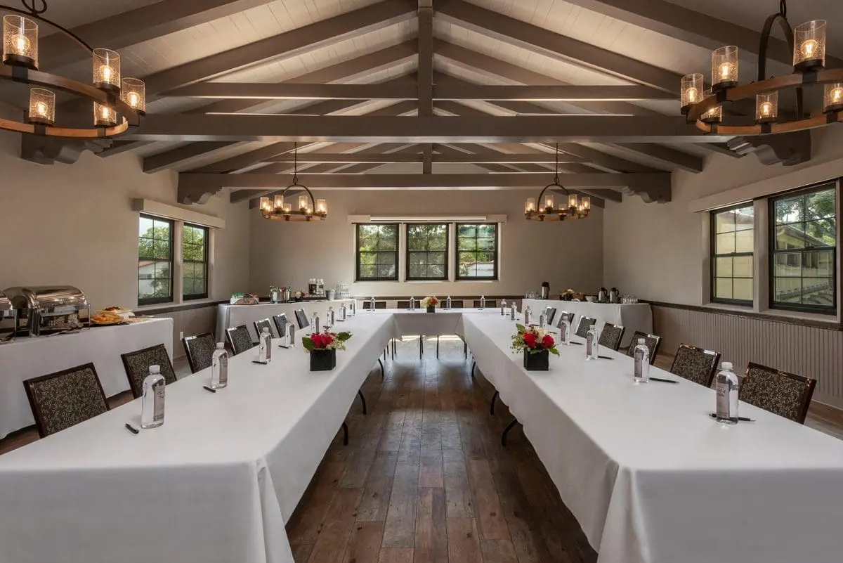 An inviting indoor dining area features rustic tables, string lights, and lush greenery, creating a cozy and charming atmosphere.