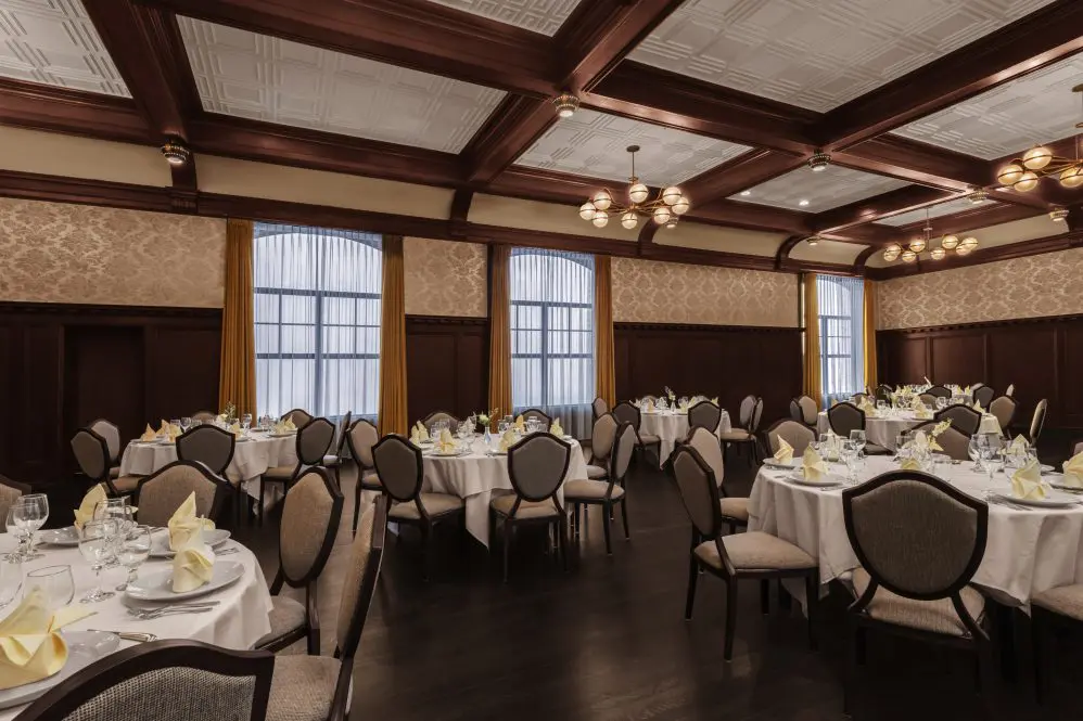 Round tables in ballroom with white linen and dark flooring.