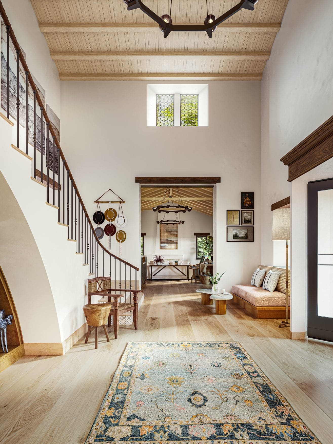 A spacious, bright entryway with high wooden ceilings, a patterned rug on light wood floors, a curved staircase, and cozy seating with pillows. Sunlight streams through upper and side windows, highlighting warm, inviting decor.