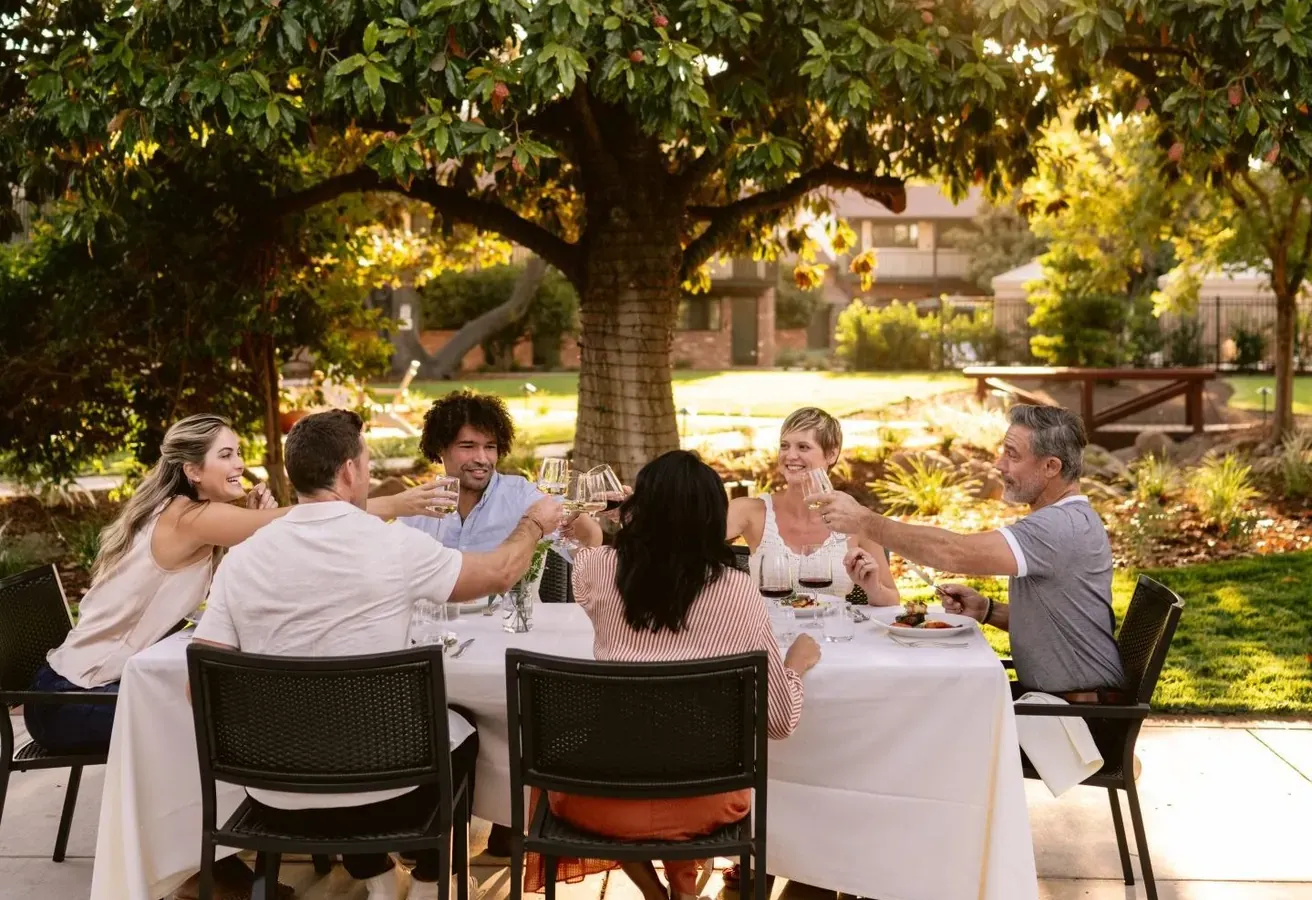 Group of people dining in a garden at golden hour.